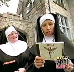 two women dressed in nun costumes are looking at a book