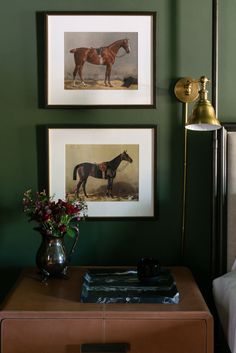 two framed pictures hang on the wall above a nightstand with a vase filled with flowers