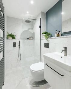 a white toilet sitting in a bathroom next to a sink and shower head mounted on a wall