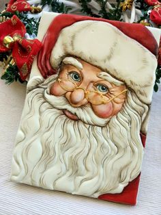 a ceramic santa clause with glasses and a beard on it's face, sitting next to christmas decorations