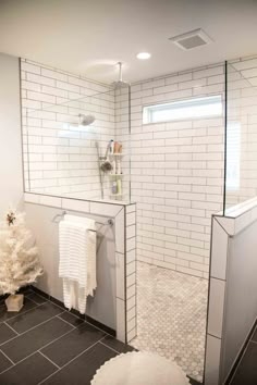 a white bathroom with black tile flooring and a christmas tree next to the shower