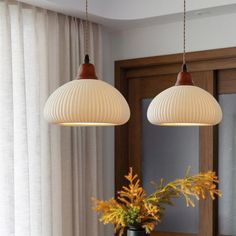 two lamps hanging over a dining room table with flowers in vases on the side