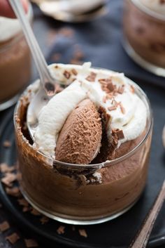 a chocolate dessert with whipped cream and chocolate shavings in it on a black plate