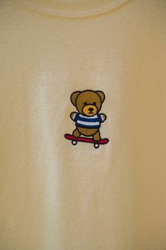 a teddy bear on a skateboard embroidered onto a t - shirt that is worn by someone