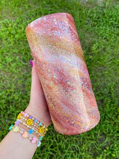 a hand holding a pink and gold glittered tube