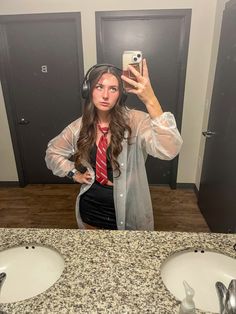 a woman taking a selfie in front of two sinks with headphones on her ears