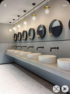 a row of sinks in a public restroom with mirrors on the wall and lights above them