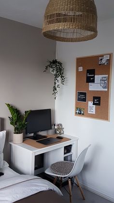 a bedroom with a bed, desk and computer on the wall next to a plant