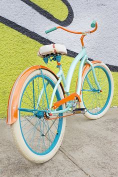 an orange and blue bicycle parked in front of a wall