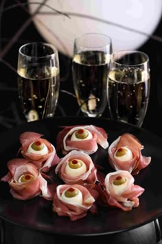 ham wrapped in prosciutto on a black plate with glasses of champagne