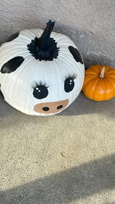 two pumpkins sitting on the ground next to each other with faces painted on them