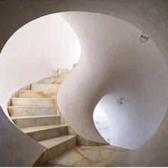 a spiral staircase with white walls and marble steps