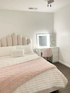 a bedroom with a bed, dresser and mirror in it's corner area that has a pink blanket on top of the bed