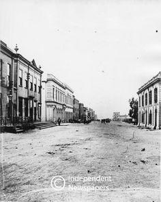 an old black and white photo of a street in the middle of town with buildings on both sides