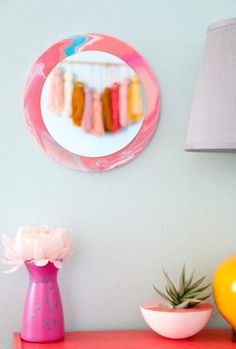 there is a pink table with a mirror on it and some vases next to it