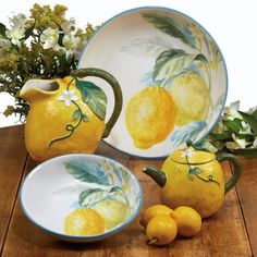 three lemons and two oranges sitting on a table next to a vase with flowers