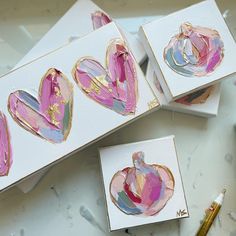 three cards with hearts painted on them sitting next to paintbrushes and watercolors