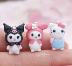 three little hello kitty charms sitting on someone's finger