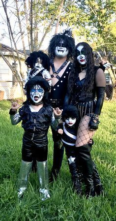 group of people dressed up in costumes posing for the camera with their faces painted black and white