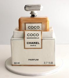 a bottle of perfume sitting on top of a white table next to another bottle that is in the shape of a box