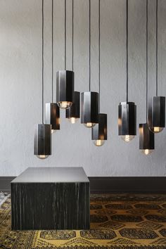 a group of lights hanging from the ceiling above a table with a stool in front of it