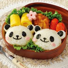 two panda bears made out of rice in a bowl with vegetables and fruit on the side