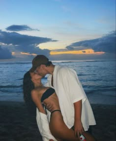 a man and woman kissing on the beach