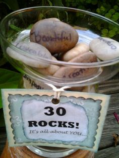 some rocks are in a glass bowl with a sign that says 30 rocks it's all about you