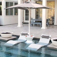 an outdoor pool with lounge chairs and an umbrella