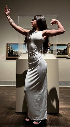 a woman in a white dress is posing for the camera with her arms stretched out