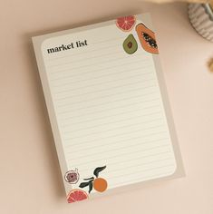 a notepad with fruit on it sitting next to a plant