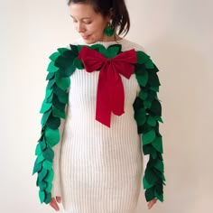 a woman in a white sweater with green and red leaves on her arms, wearing a bow tie