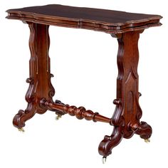 an antique wooden table with wheels on the legs and a carved wood top, isolated against a white background