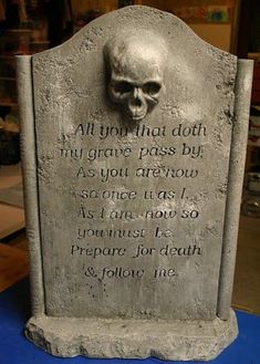 a tombstone with a skull on it and a poem written in human language next to it