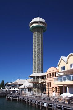 the water tower is next to some buildings and umbrellas in front of an ocean side restaurant