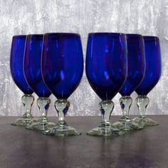 four blue wine glasses sitting on top of a wooden table