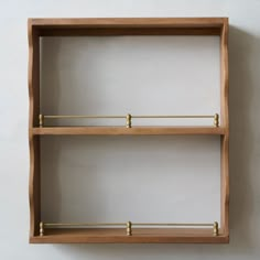 two wooden shelves with brass handles against a white wall