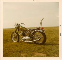 an old photo of a motorcycle parked in the grass with no one on it's bike