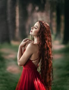 a woman with long red hair wearing a red dress and looking up into the sky