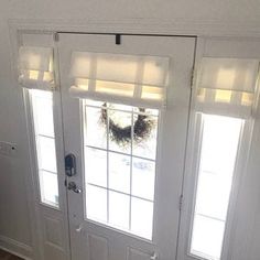 a white door with two sidelights and a wreath on the top window sill