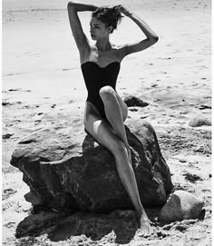 a woman in a bathing suit sitting on a rock