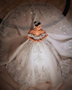 a woman in a wedding dress is sitting on the floor with her hands behind her back