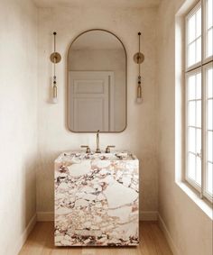 a bathroom with a marble sink and mirror on the wall, along with wooden flooring