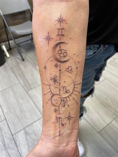 a person with a tattoo on their arm that has the moon and stars in it