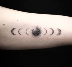 an arm with five phases of the sun and moon on it, in black ink