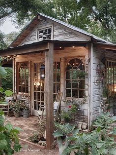 a small building with lots of windows and plants in the front yard, surrounded by greenery