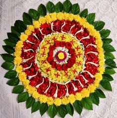 an overhead view of a flower arrangement on a white tablecloth with green leaves and red flowers