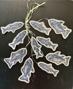 some blue and white fish are hanging from a string on a black surface with green cord