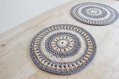 two circular crocheted rugs sitting on top of a wooden table