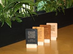 three small wooden blocks sitting on top of a table next to some green planters